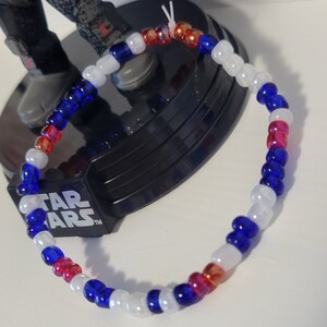 Pu&ograve; includere: Un braccialetto di perline rosso, bianco e blu. Le perline sono disposte in un motivo che ricorda la bandiera italiana.