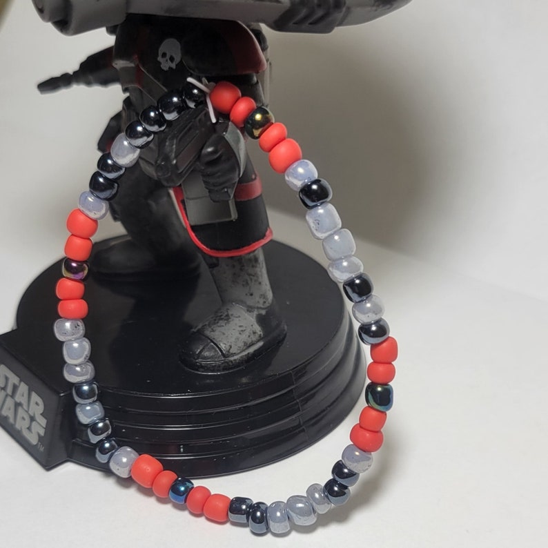 Puede incluir: Un brazalete de cuentas rojas, negras y blancas con cuentas de diferentes tama&ntilde;os.