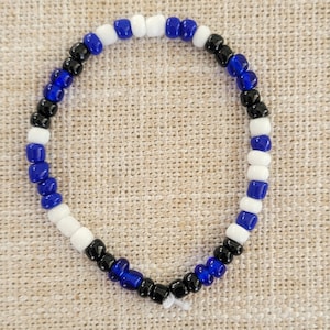 Pu&ograve; includere: Un braccialetto di perline nere, bianche e blu. Il braccialetto &egrave; realizzato con piccole perline rotonde e infilate insieme in un motivo ripetitivo.