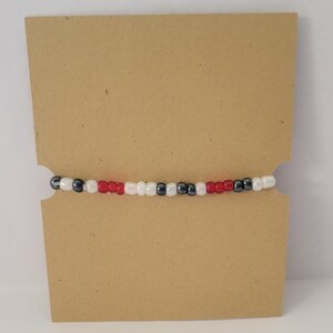May include: A beaded bracelet with red, white and black beads.
