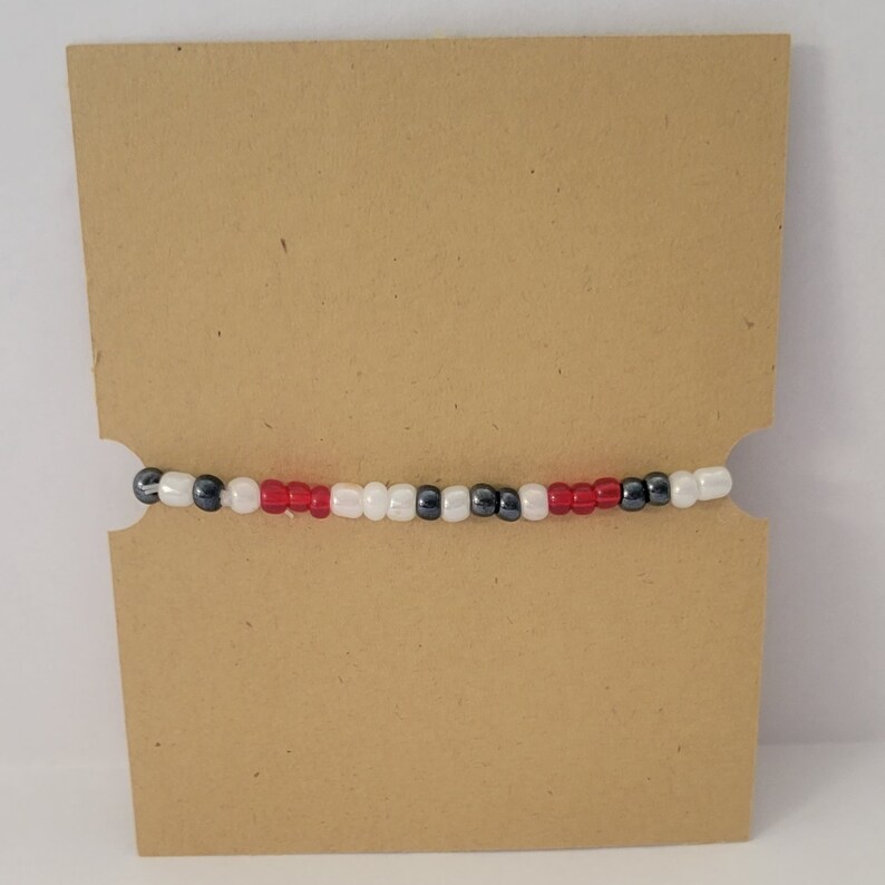 May include: A beaded bracelet with red, white and black beads.
