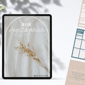 Könnte beinhalten: Ein digitales Tablet zeigt eine Grafik mit dem Text "MEIN Angsttagebuch" in einem weißen Bogen auf beigefarbenem Hintergrund. Das Hintergrundbild ist ein weißer Stoff mit einem Trockenblumenarrangement. Der Text "@yourplacetocalm" befindet sich am unteren Bildschirmrand.