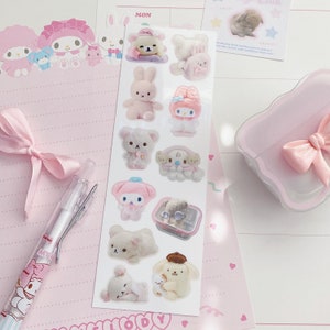 May include: A sheet of pink and white stickers featuring various cartoon characters. The characters include a bear, a rabbit, a cat, and a bird. The stickers are on a white background with a pink border.