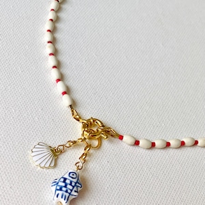 Fischcharme und Muschelanhängerhalskette. Traumhafte Halskette. Rot und weiß perlenbesetzte Bettelkette. Sommerliche Halskette. Maritime Bettelkette.