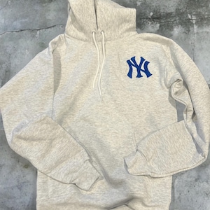 May include: A grey hooded sweatshirt with a blue embroidered New York Yankees logo on the front.