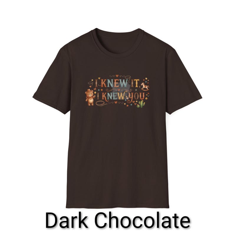 Puede incluir: Una camiseta de manga corta color marr&oacute;n chocolate oscuro con un estampado gr&aacute;fico que incluye el texto I KNEW IT I KNEW YOU. El dise&ntilde;o muestra un peque&ntilde;o oso con sombrero de vaquero, un caballito de madera, un cactus, estrellas y corazones.