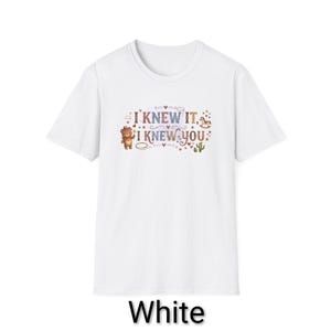 Puede incluir: Una camiseta blanca de manga corta con un estampado gr&aacute;fico que incluye el texto I KNEW IT, I KNEW YOU. El dise&ntilde;o presenta un oso marr&oacute;n con sombrero, un peque&ntilde;o caballo balanc&iacute;n, un cactus verde y varios corazones y estrellas en tonos suaves.