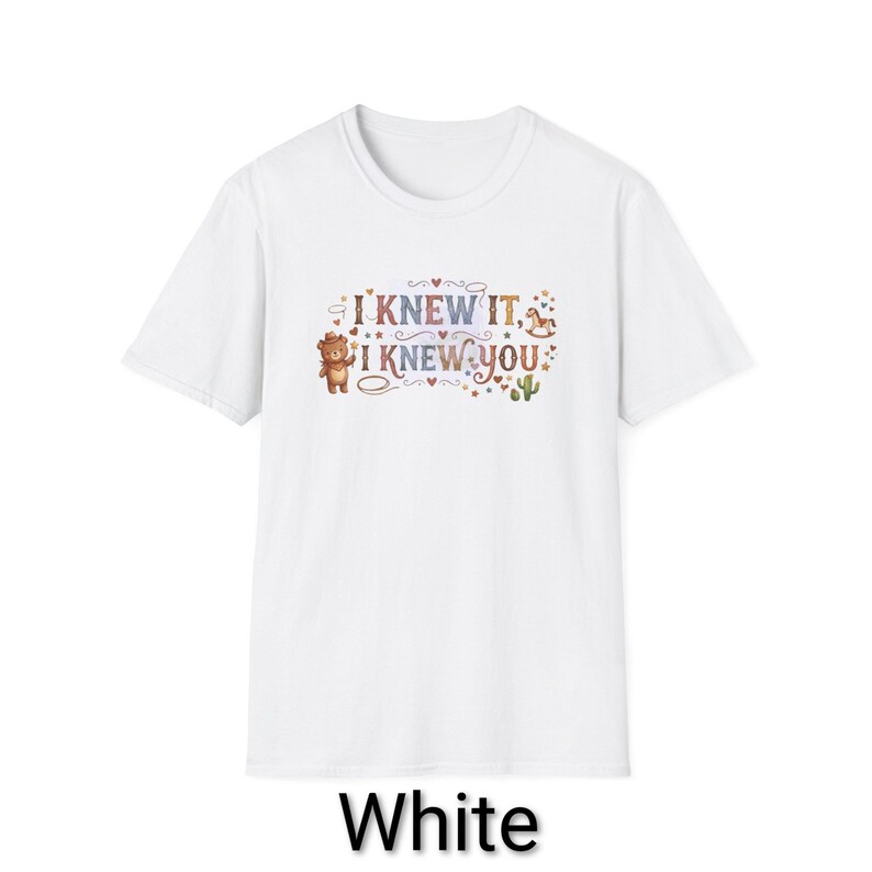 Puede incluir: Una camiseta blanca de manga corta con un estampado gr&aacute;fico que incluye el texto I KNEW IT, I KNEW YOU. El dise&ntilde;o presenta un oso marr&oacute;n con sombrero, un peque&ntilde;o caballo balanc&iacute;n, un cactus verde y varios corazones y estrellas en tonos suaves.