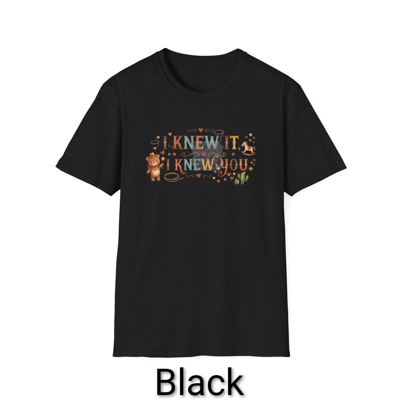 Puede incluir: Una camiseta negra de manga corta con un estampado gr&aacute;fico que incluye el texto I KNEW IT, I KNEW YOU. El dise&ntilde;o muestra un oso de peluche marr&oacute;n con sombrero de vaquero, un caballito balanc&iacute;n, un cactus verde y varios corazones y estrellas.