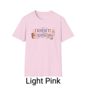 Puede incluir: Una camiseta de manga corta de color rosa claro con un estampado gr&aacute;fico que incluye el texto I KNEW IT, I KNEW YOU. El dise&ntilde;o muestra un oso marr&oacute;n con sombrero, un caballito balanc&iacute;n, un cactus verde y varios corazones y estrellas.