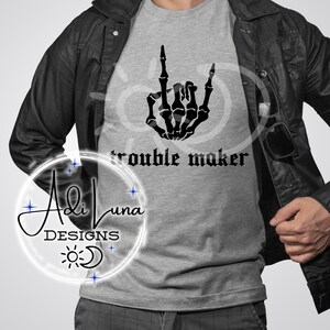 Könnte beinhalten: Ein graues T-Shirt mit einer schwarzen Skeletthand, die ein Rock'n'Roll-Zeichen macht. Der Text "trouble maker" ist unter der Hand aufgedruckt.