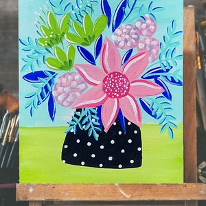 May include: A painting of a bouquet of flowers in a black and white polka dot vase. The flowers are pink, green, and blue. The background is a light blue.