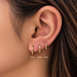 May include: Three gold-toned hoop earrings in varying sizes, labelled 12mm, 10mm, and 8mm, arranged in a row on an earlobe. The hoops have a smooth, polished finish and a simple circular design, showcasing the different diameters clearly.