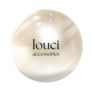 May include: A spherical, off-white, lustrous object with a smooth, reflective surface. Centered on the sphere is the black text 'louci' in a serif font, with the word 'accessories' in a smaller, simpler font directly underneath the brand name.
