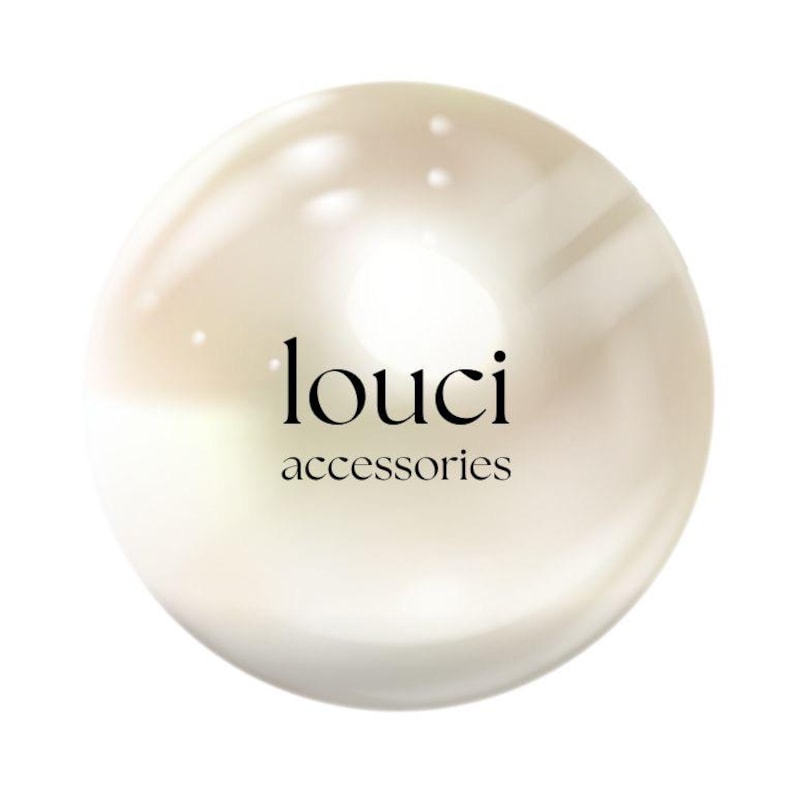 May include: A spherical, off-white, lustrous object with a smooth, reflective surface. Centered on the sphere is the black text 'louci' in a serif font, with the word 'accessories' in a smaller, simpler font directly underneath the brand name.
