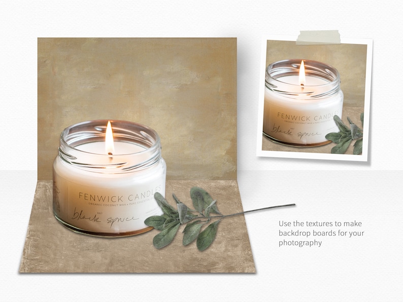 Op de afbeelding: Een witte kaars in een glazen pot met een zwart label waarop "FENWICK CANDLES" en "black spruce" staat. De kaars is aangestoken en er ligt een takje groen naast.