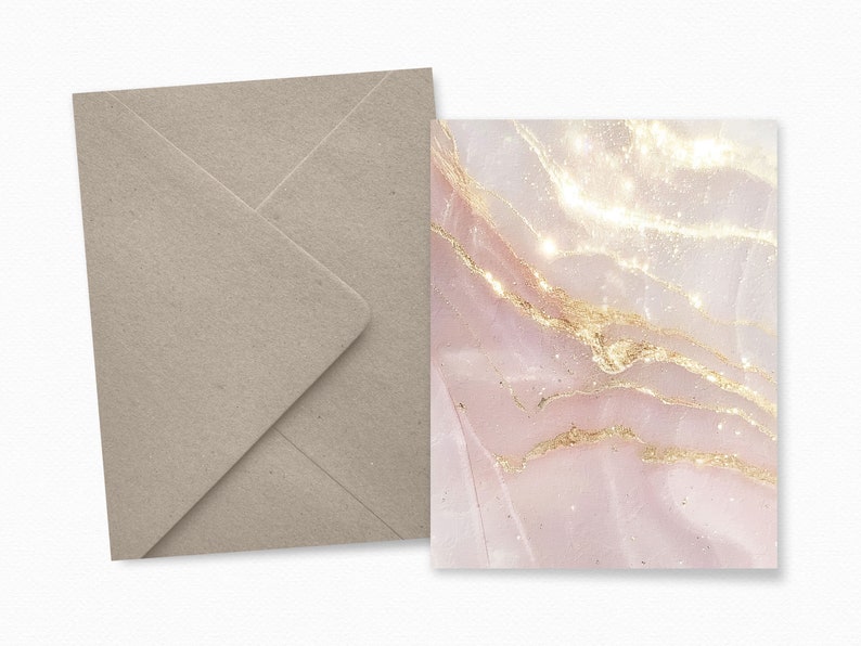 May include: A stationery set featuring a light pink and gold marble design. The card has a shimmering effect with gold veins. A matching light brown envelope is included, creating an elegant and cohesive look. Ideal for invitations or special notes.