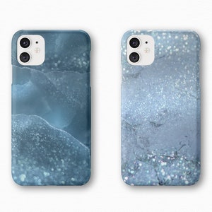 May include: Two phone cases with a blue and white marble design. The cases have a glittery finish.