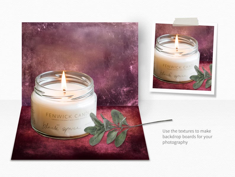 May include: A glass jar candle with a white wax and a lit wick. The jar has a label that reads "Fenwick Candles" and "Black Spruce". The candle is sitting on a textured, burgundy background with a sprig of green foliage.