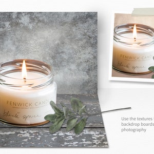 Op de afbeelding: Een brandende kaars in een glazen pot met een label waarop "FENWICK CANDLES" en "black spruce" staat. De kaars staat op een rustiek houten oppervlak met een takje groene bladeren.