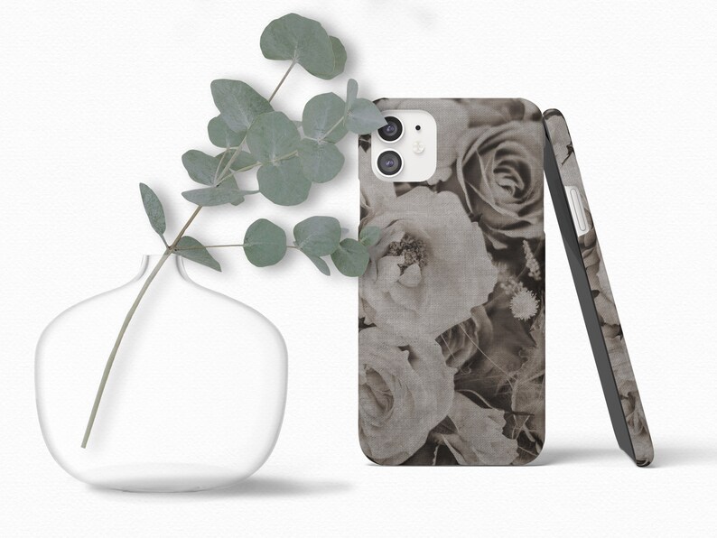 May include: A phone case with a floral design featuring black and white roses. The case is made of a textured material and has a subtle linen look.