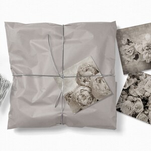 May include: A package wrapped in brown paper with silver twine and tied with a bow. The package contains three black and white floral prints.