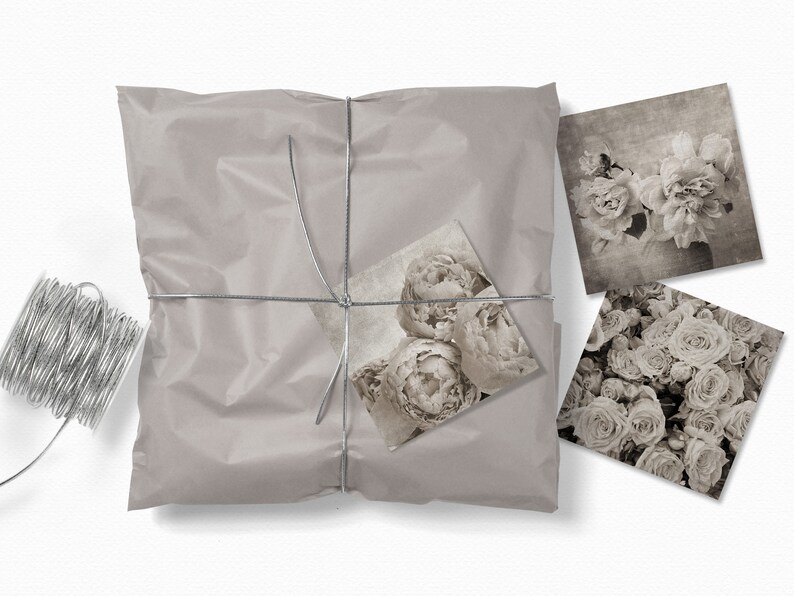 May include: A package wrapped in brown paper with silver twine and tied with a bow. The package contains three black and white floral prints.