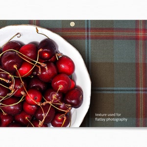 May include: A white bowl filled with bright red cherries on a green and red plaid background. The text "texture used for flatlay photography" is visible in the bottom right corner of the image.