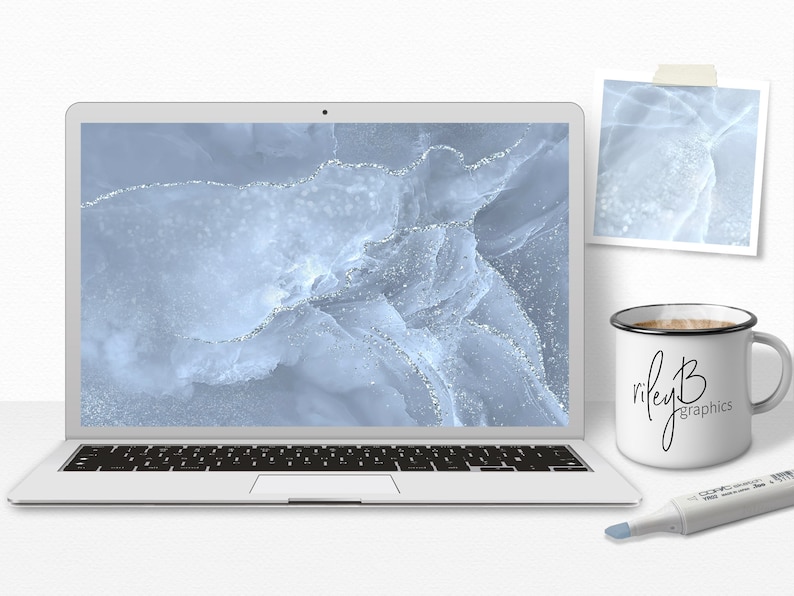 May include: A laptop computer with a blue and silver abstract design on the screen. The laptop is sitting on a white surface with a white mug and a silver marker.