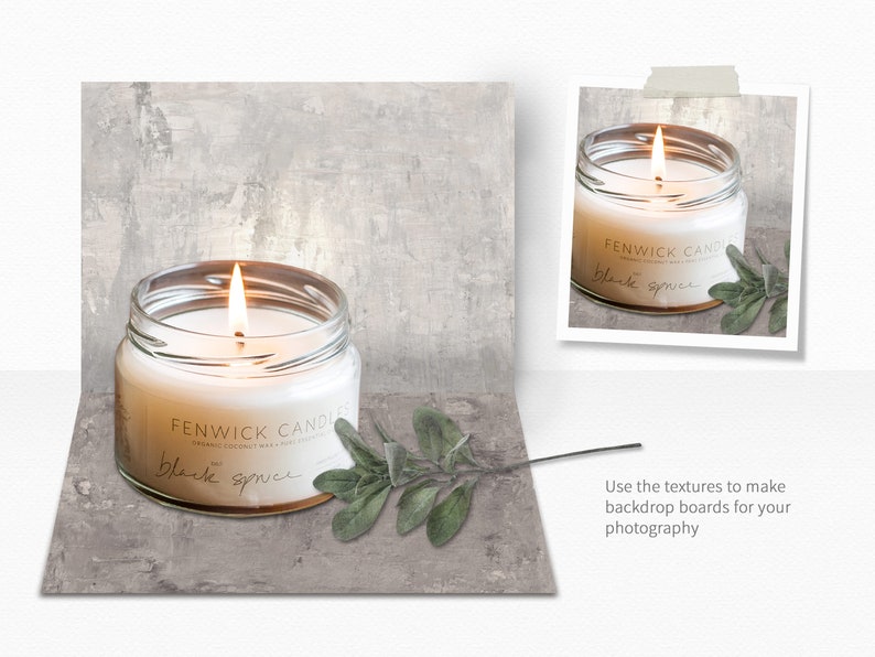 May include: A white candle in a clear glass jar with a gold lid. The candle is lit and the flame is visible. The jar has a label that reads "FENWICK CANDLES" and "black spruce". There is a sprig of green leaves next to the candle.