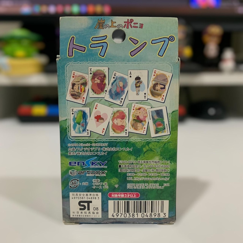 May include: A deck of playing cards featuring illustrations from the animated film "Ponyo". The box is predominantly blue and green, with Japanese text and images of the cards displayed. The cards feature various characters and scenes.