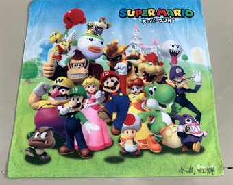 May include: A green Super Mario Bros. themed towel with a large group of characters including Mario, Luigi, Peach, Donkey Kong, Yoshi, and Bowser. The towel has the text "SUPER MARIO" and "スーパーマリオ" in Japanese.