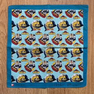 May include: A light blue square handkerchief with a repeating pattern of yellow, red, and white robot illustrations. The border is a darker shade of blue. Japanese text is visible.