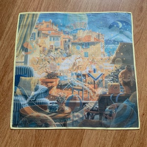 May include: A square handkerchief with a detailed illustration of a European town scene. The design features buildings, furniture, and a night sky with a moon and stars. The handkerchief has a yellow border.