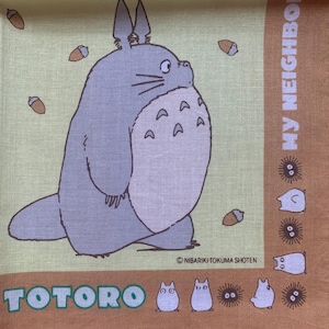 K&ouml;nnte beinhalten: Ein quadratischer, hellgr&uuml;ner und brauner Stoff mit der Figur Totoro aus dem Zeichentrickfilm Mein Nachbar Totoro. Das Bild enth&auml;lt den Text "TOTORO" und "MY NEIGHBOR". Das Design umfasst Eicheln und andere Charaktere.