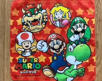 May include: A red Super Mario handkerchief with images of Mario, Yoshi, Princess Peach, Luigi, Bowser, and Toad. The background has a star pattern, and the Super Mario logo is visible.