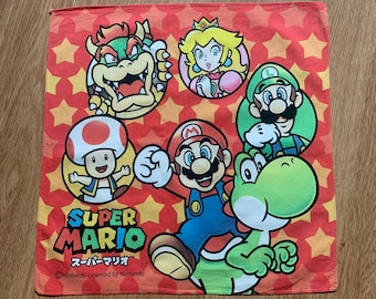 May include: A red bandana with a white star pattern featuring characters from the Super Mario video game series. The characters include Mario, Luigi, Bowser, Toad, and Yoshi. The bandana has the text "Super Mario" and "スーパーマリオ" in Japanese.