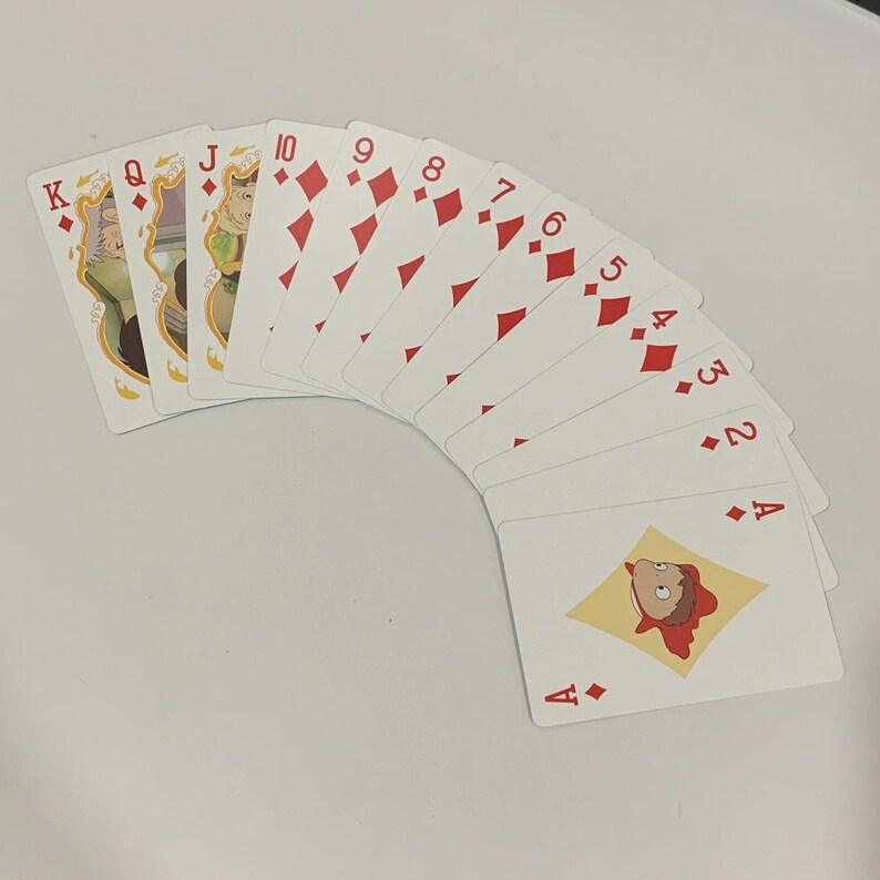 May include: A deck of playing cards fanned out, featuring the suits of diamonds and face cards with character illustrations. The cards are white with red diamond symbols and character art.