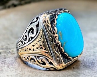 May include: A silver ring with a turquoise stone set in a gold-toned filigree design.