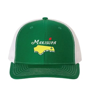 May include: Green and white trucker hat with a yellow and green golf course graphic and the text "Makisupa" in white.
