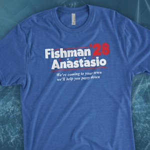 May include: A blue t-shirt with the text "Fishman '28 Anastasio" in white with a red star. The text below reads "We're coming to your town we'll help you party down."