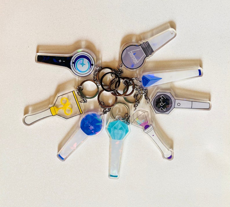 May include: A set of nine colorful keychains featuring various designs, including a blue and white star, a blue and white heart, a blue and white circle, a blue and white square, a blue and white triangle, a blue and white diamond, a blue and white pentagon, a blue and white hexagon, and a blue and white octagon.