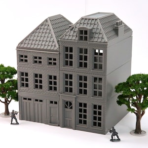 Op de afbeelding: Een grijs, drielaags model van een gebouw met een zadeldak, ramen en een deur. Het gebouw is gemaakt van plastic en is ontworpen voor gebruik in een miniatuursetting.