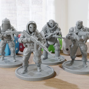 May include: Four gray plastic figurines of soldiers wearing helmets and holding guns. The soldiers are standing on round bases.