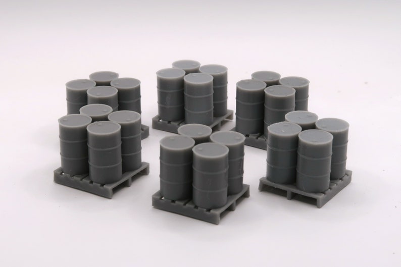 May include: A set of gray plastic model barrels stacked on pallets. The barrels are arranged in three groups of six, with each group on a separate pallet.