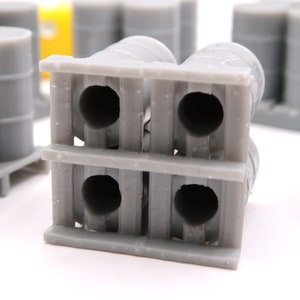 May include: A gray pallet with four gray barrels stacked on top. The barrels have a circular opening on each end.