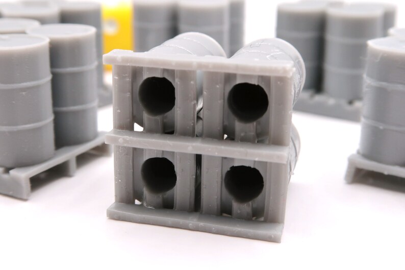 May include: A gray pallet with four gray barrels stacked on top. The barrels have a circular opening on each end.