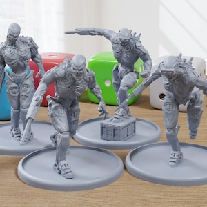 Peut inclure: Quatre figurines miniatures en plastique gris de robots humanoïdes avec une sculpture détaillée. Les figurines sont posées dans des positions dynamiques et sont posées sur des bases circulaires grises. Une figurine tient une petite boîte grise.