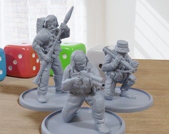 May include: Three gray plastic toy soldiers, each holding a different weapon, are standing on circular bases. The soldiers are wearing military uniforms and helmets. The soldiers are on a wooden table with three dice in the background.