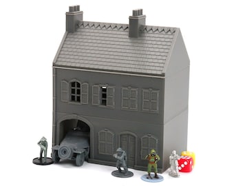 May include: A gray plastic model of a two-story building with a garage door, windows, and a roof. The building is surrounded by miniature figures and dice.
